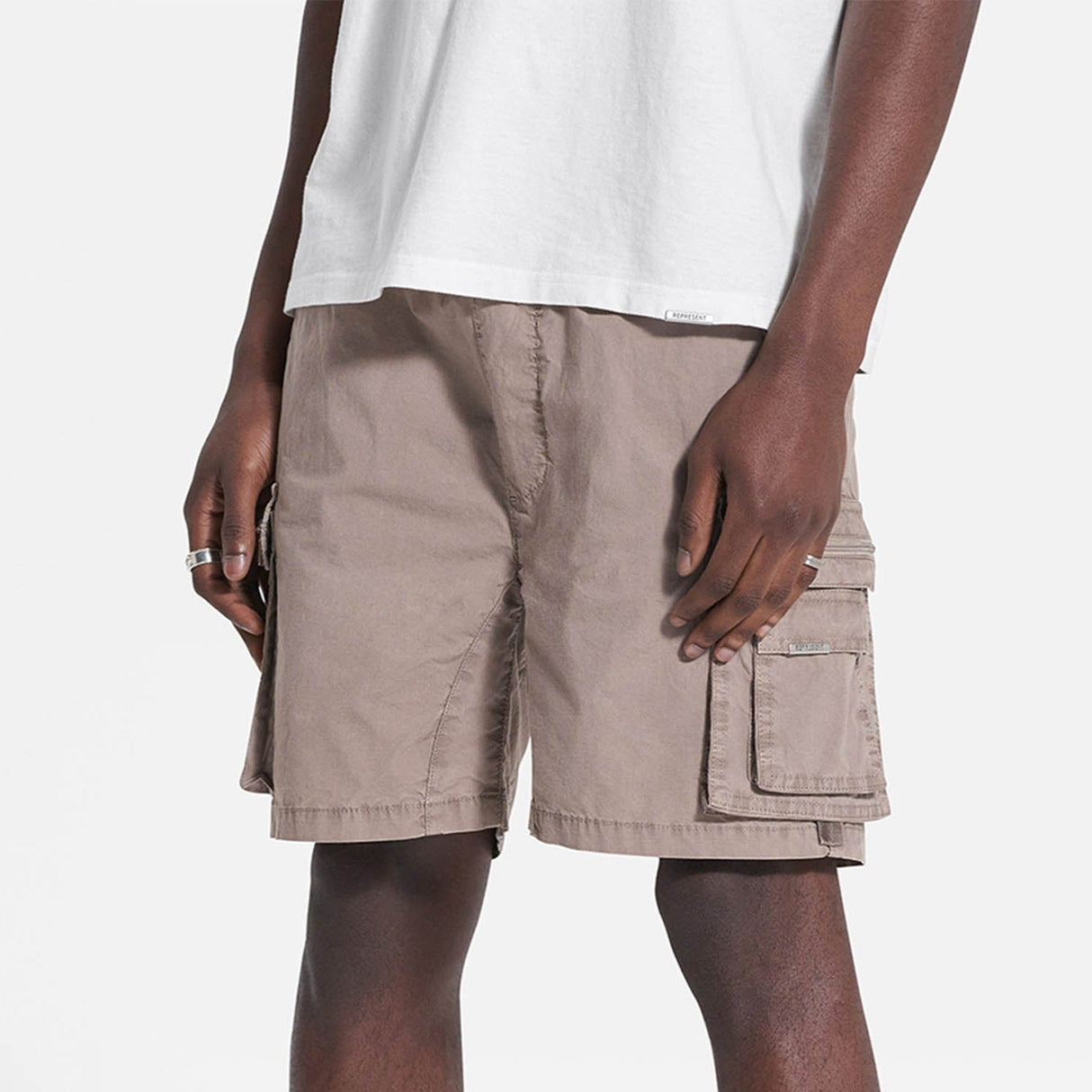 Represent cargo shorts in stone color with multiple pockets, casual fit, and durable fabric, perfect for everyday wear.