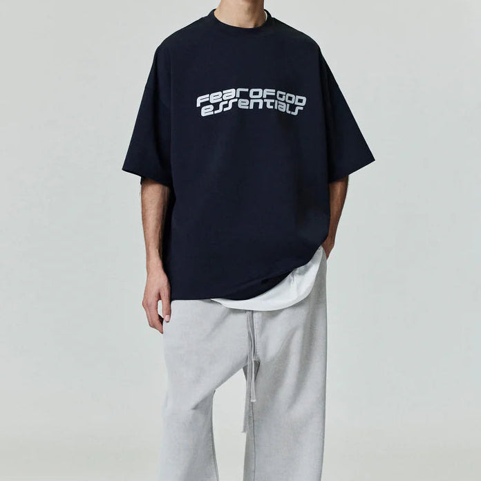 Fear of God Essentials reflective logo 90s black T-shirt, casual apparel with a prominent reflective logo on front.