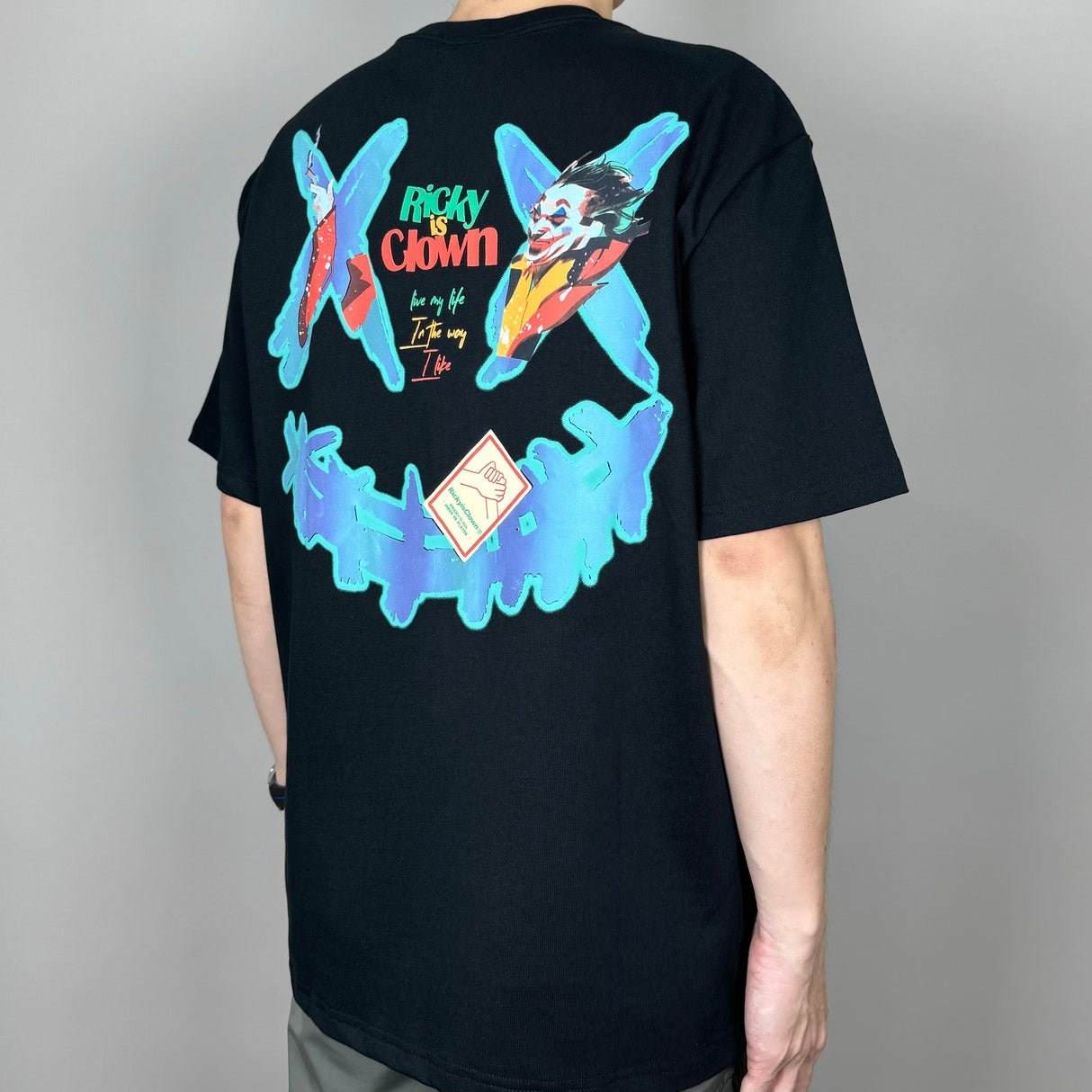 Black Rickyisclown Joker Laser Reflective Smiley Tee featuring a bold smiley face design on the front.