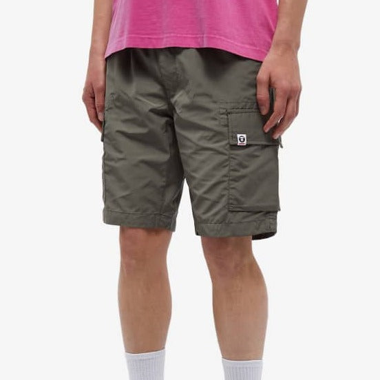 Olive green AAPE by Bathing Ape badge cargo shorts featuring multiple pockets and branded logo details.