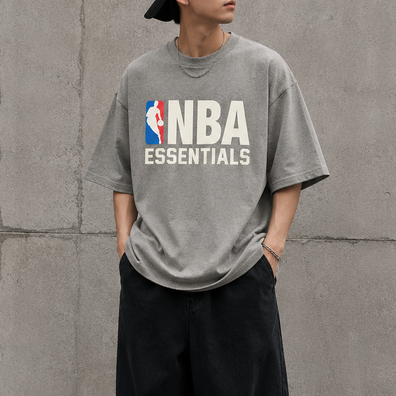 Fear of God Essentials NBA 90s Heavyweight Tee in concrete heather, showing the relaxed fit and classic design on the front.