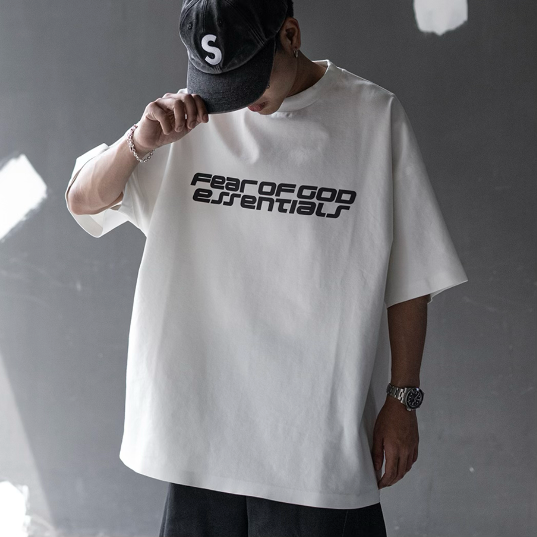 Fear of God Essentials Ivory Reflective Logo Ponte 90s Tee, close-up of upgraded fabric and reflective logo on front.