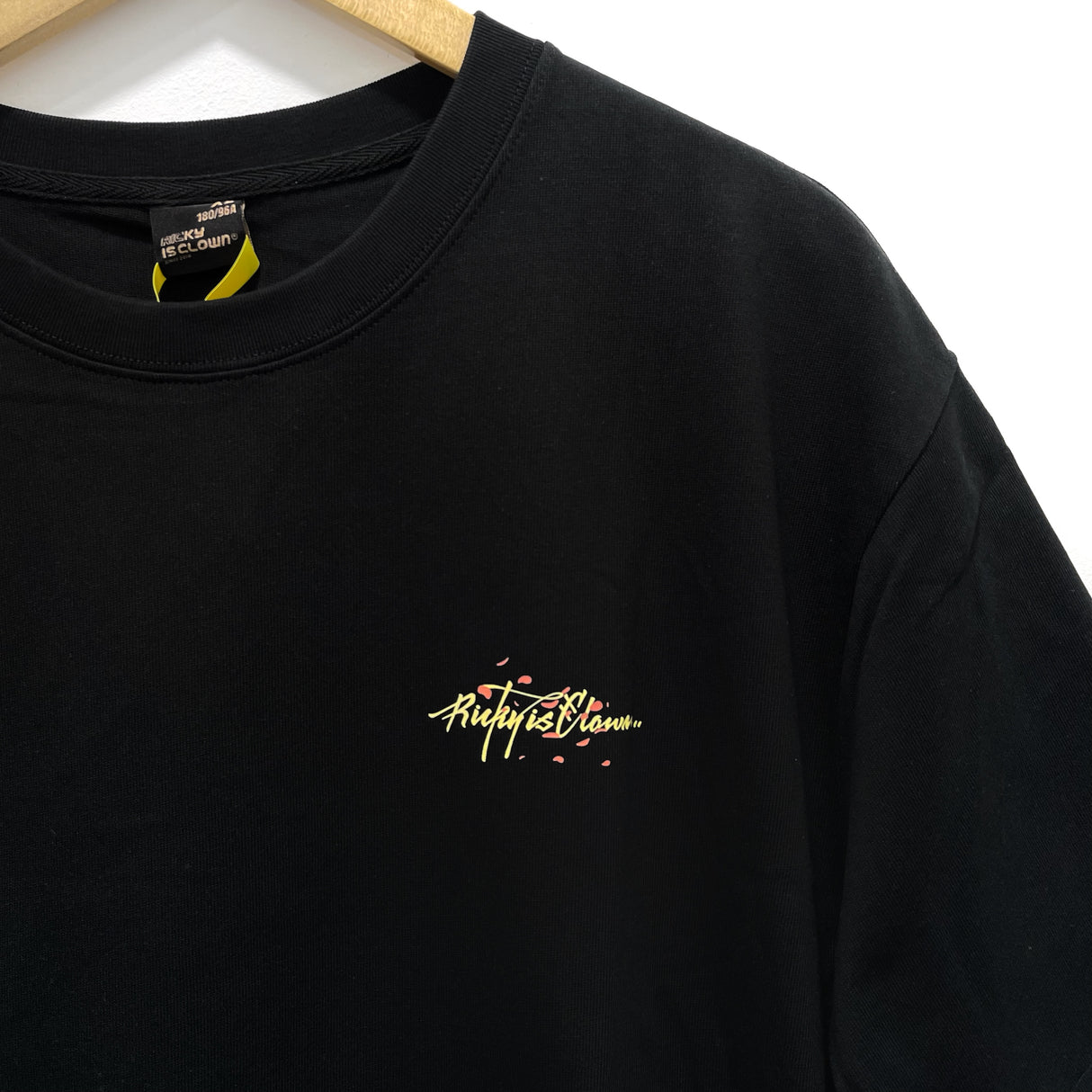 RICKYISCLOWN Sakura Sunset Tee in black featuring vibrant cherry blossom design, casual apparel for streetwear style.