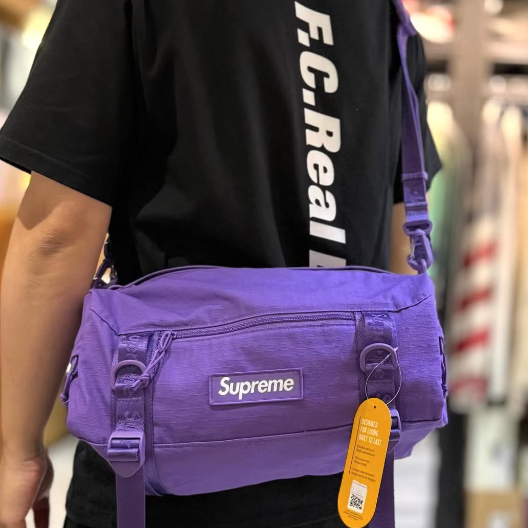 Supreme purple box logo utility bag with adjustable strap and zippered compartments, designed for versatile carrying.
