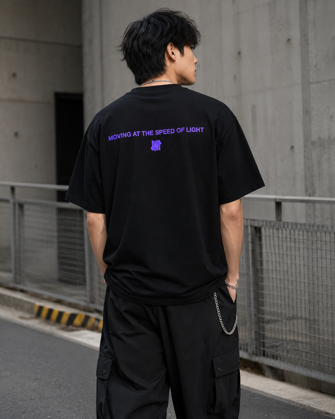 Black Undefeated Wrap Tee displayed on a hanger, showcasing its relaxed fit and stylish design.