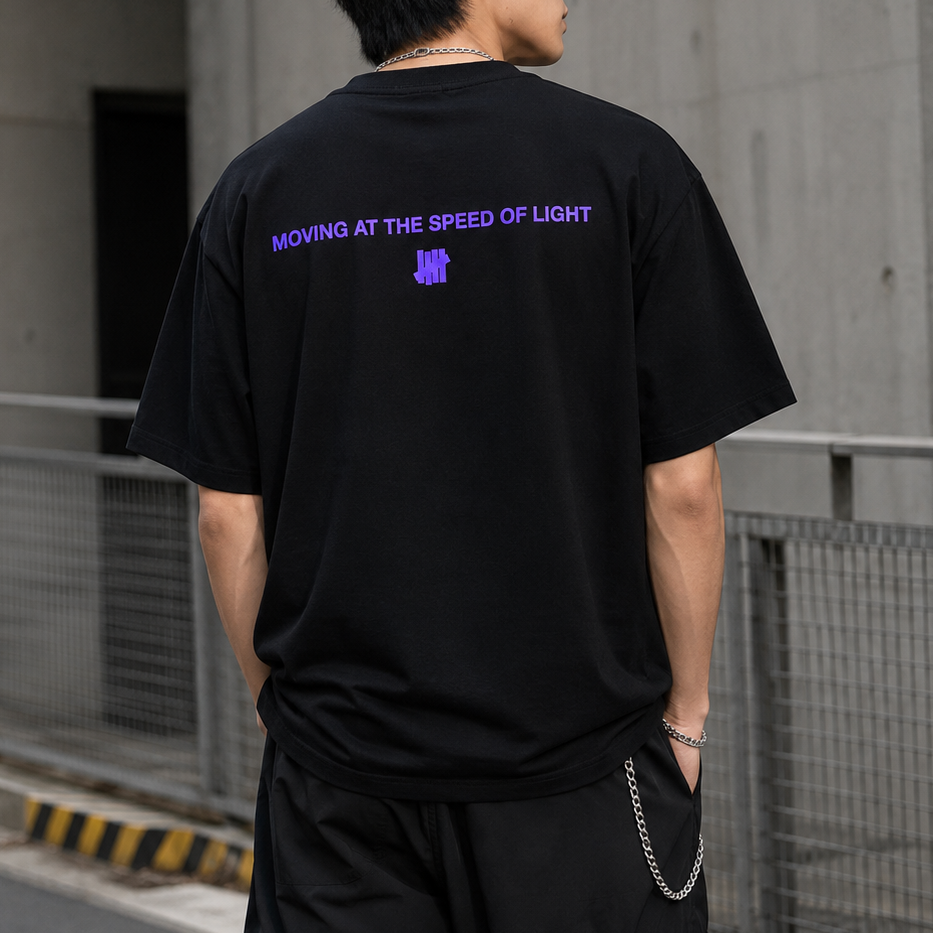 Black Undefeated Wrap Tee displayed flat, showing the front design and breathable fabric for casual streetwear style.