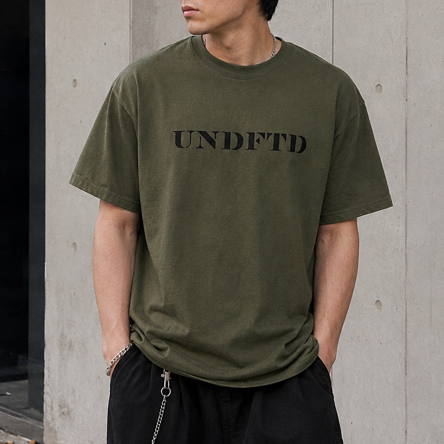Olive green UNDEFEATED Stencil Logo T-shirt with front graphics, casual fit, and short sleeves.