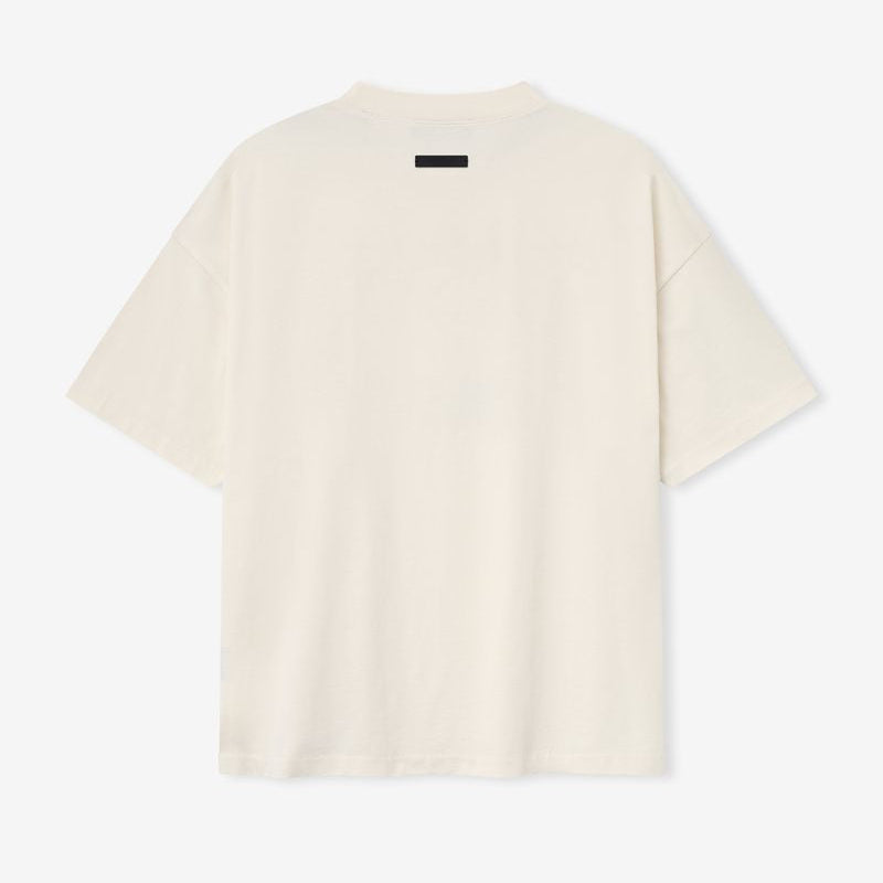 Cream Fear of God Essentials X NBA 90s heavyweight T-shirt displayed on a hanger, showcasing the relaxed fit and bold graphic print.