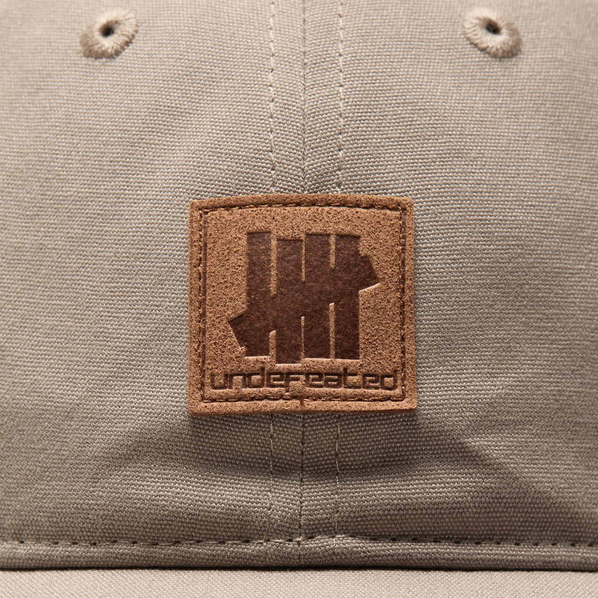 Undefeated Patch Logo Snapback hat in khaki with adjustable strap, canvas material, and branded patch detail.