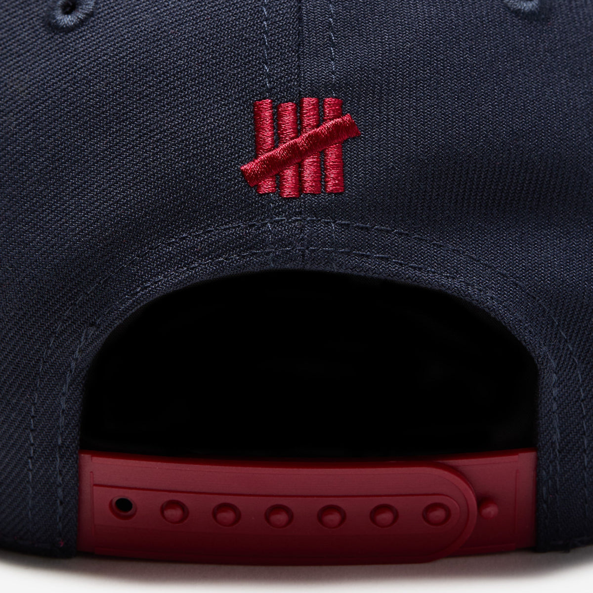 Navy and red Undefeated Play Dirty Snapback hat featuring adjustable snapback closure and embroidered branding.
