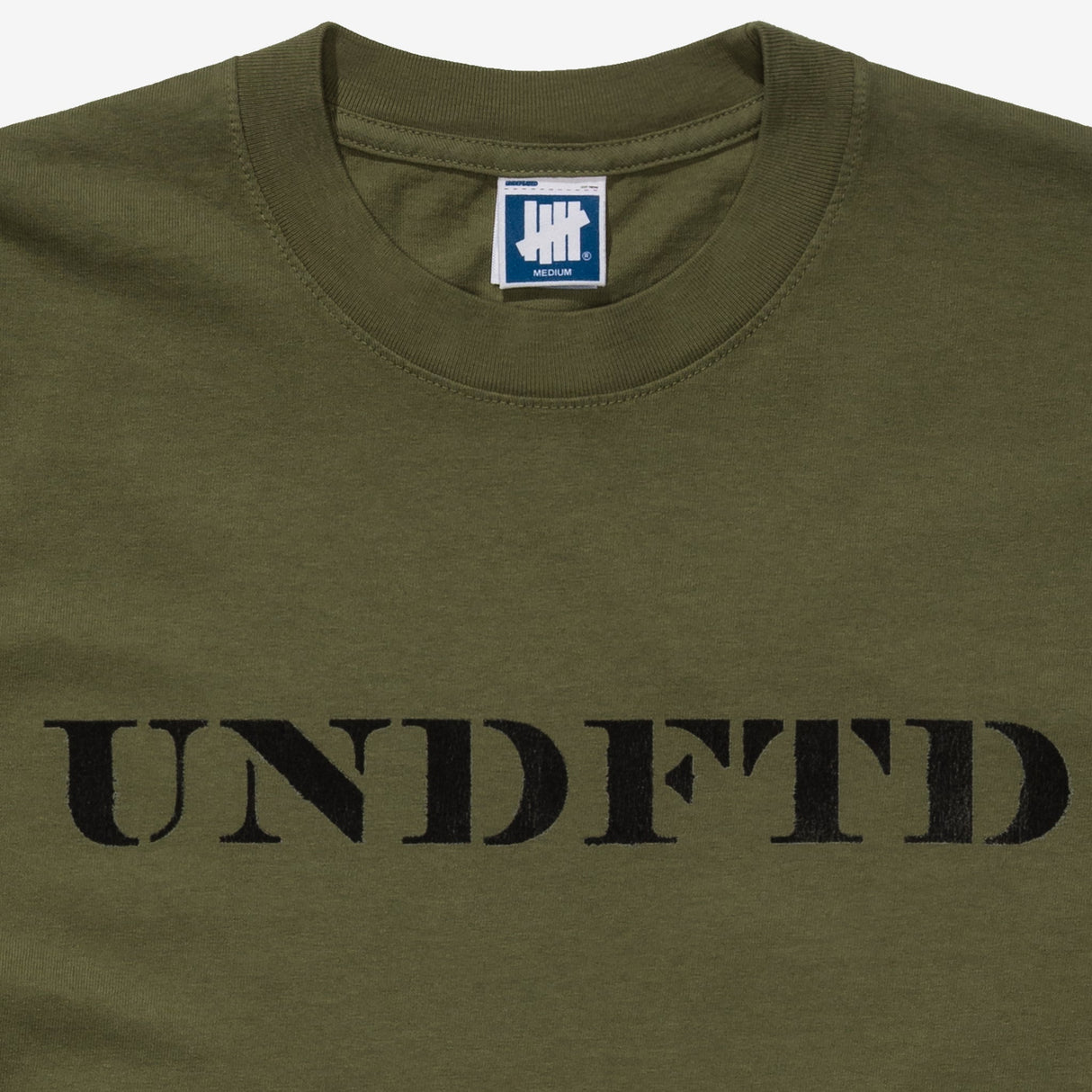 Olive green Undefeated Stencil Logo T-shirt with front graphic, casual short sleeve apparel by UNDEFEATED, shown on a flat surface.