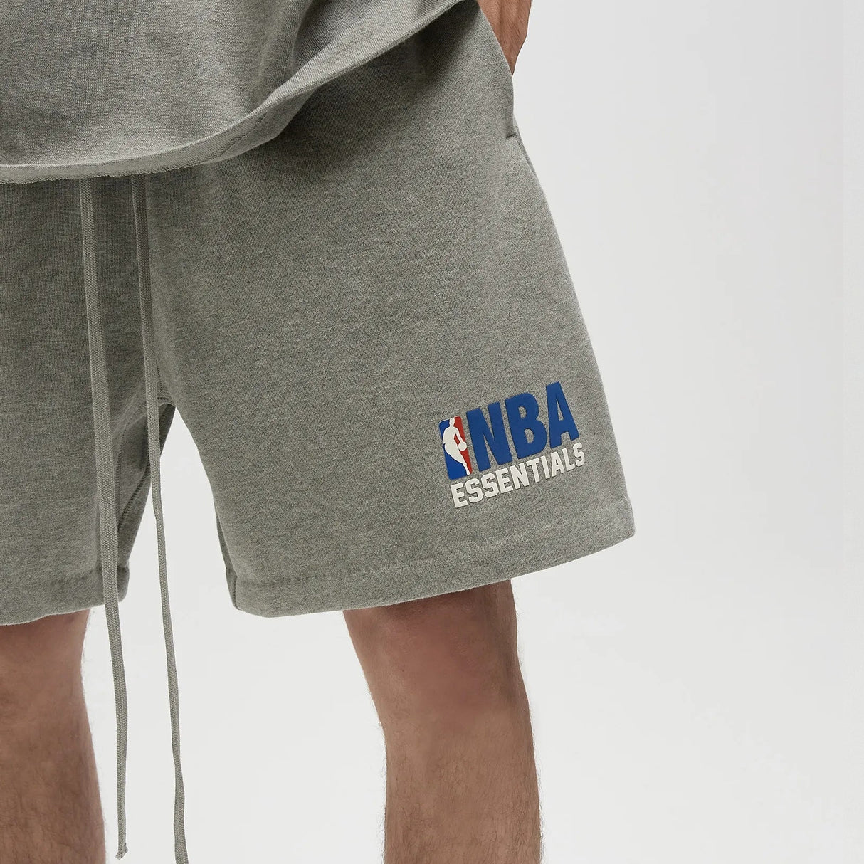 Fear Of God Essentials NBA logo sweat shorts in concrete heather, featuring relaxed fit and sporty design, casual apparel for everyday wear.