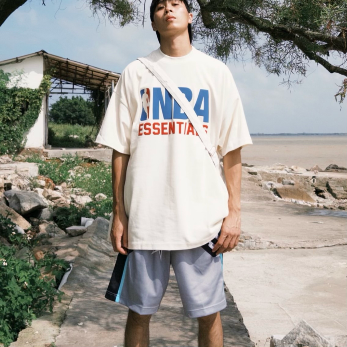 Cream Fear of God Essentials X NBA 90s Heavyweight Tee, casual crewneck shirt with NBA logo and vintage 90s design.