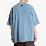 Fear of God Essentials Campus 90s Heavyweight Tee in faded coastal color, showing the relaxed fit and textured fabric.