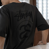 Faded black Stussy Stock Logo Tee featuring the brand's signature logo on the front, casual streetwear apparel.