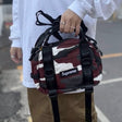 Supreme red camo box logo mini duffle bag with black zipper and adjustable strap, compact and stylish for travel or daily use.