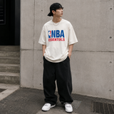 Cream Fear of God Essentials NBA 90s heavyweight t-shirt featuring bold NBA logo and classic fit, casual streetwear style.