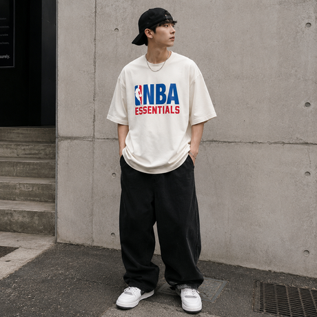 Cream Fear of God Essentials NBA 90s heavyweight t-shirt featuring bold NBA logo and classic fit, casual streetwear style.