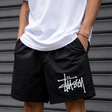 Black Stussy Basic Big Logo nylon shorts with a relaxed fit and bold logo print, perfect for casual summer wear.