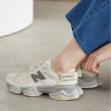 New Balance 9060 Mule sneakers in off-white and mauve with a sleek design and comfortable sole, displayed on a plain background.