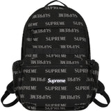 Supreme black reflective monogram logo backpack with silver logo detail, featuring multiple compartments and adjustable straps.