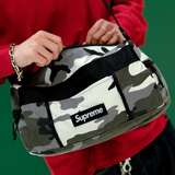 Supreme Utility Sling Bag in snow camo pattern with adjustable strap and front pocket, designed for casual and outdoor use.