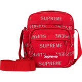 Supreme reflective monogram logo shoulder bag in red with silver logo detail, stylish and compact for everyday use.