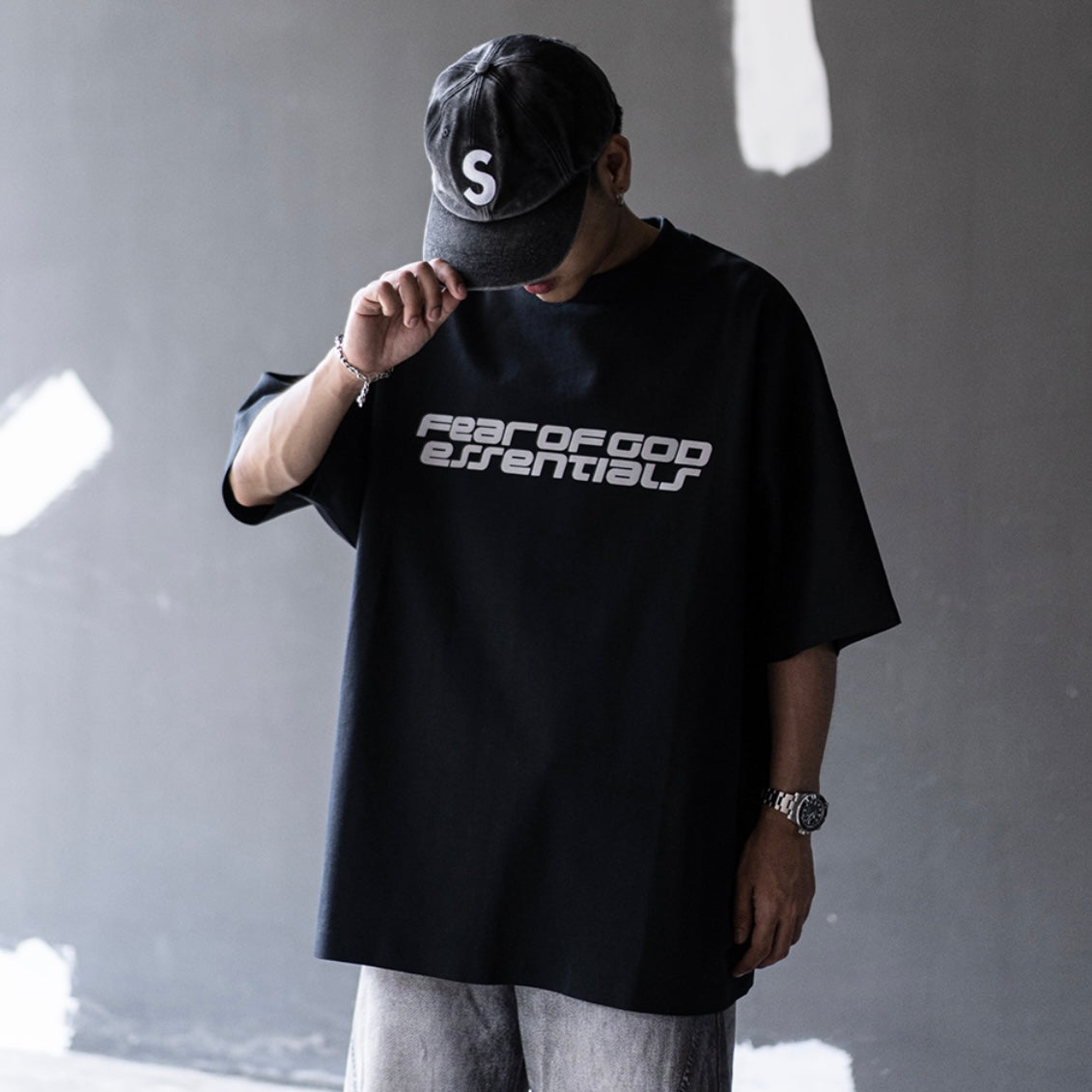Fear of God Essentials black reflective logo 90s T-shirt, casual apparel with retro style and bold branding, front view.