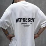 White REPRESENT Owners Club Logo Tee featuring a prominent club logo on the front, casual crew neck design.