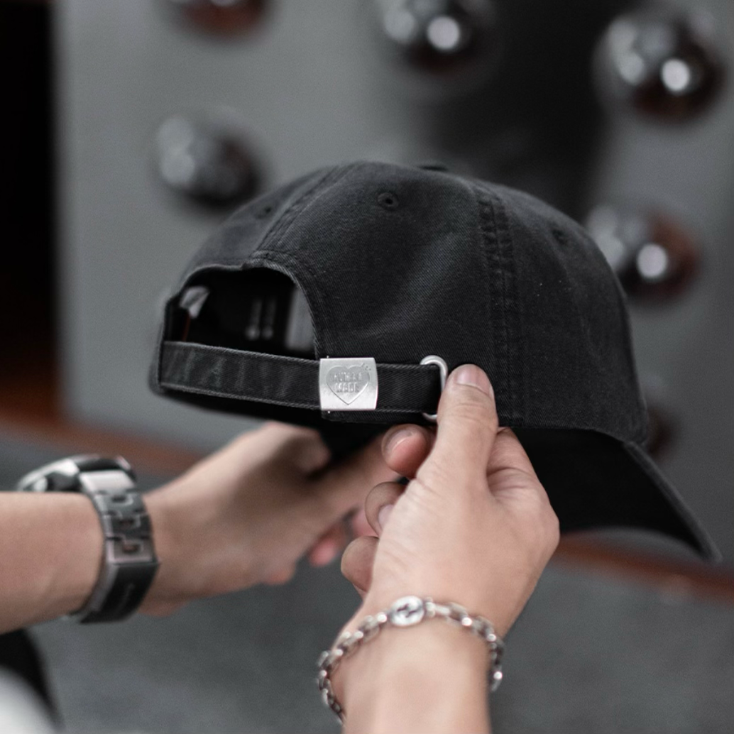 Human Made black 6-panel cap with heart logo, stylish headwear featuring a classic design and adjustable strap.