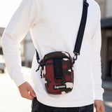 Supreme box logo sling bag in red camo fabric with adjustable strap and front logo patch, casual accessory for everyday use.