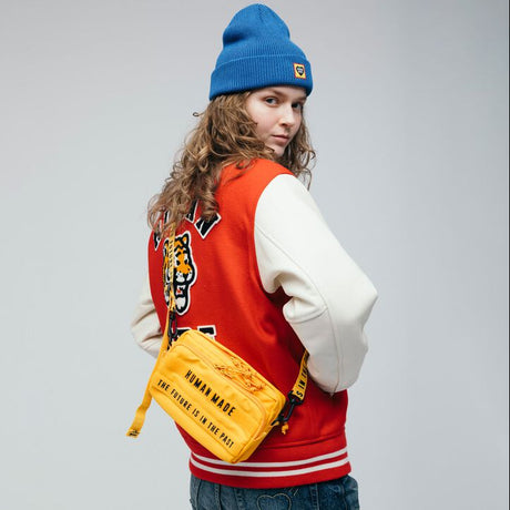 Yellow Human Made military sling bag with adjustable strap and multiple compartments, stylish and functional accessory.