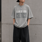 Fear of God Essentials X Celtics NBA heavyweight tee in concrete, showing the front view with team logo and relaxed fit.