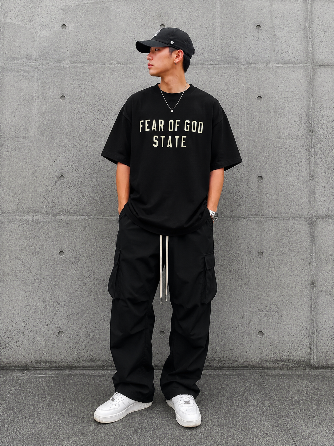 Black Fear of God Essentials 90's Tee displayed on a hanger, showcasing the casual streetwear style and soft cotton fabric.