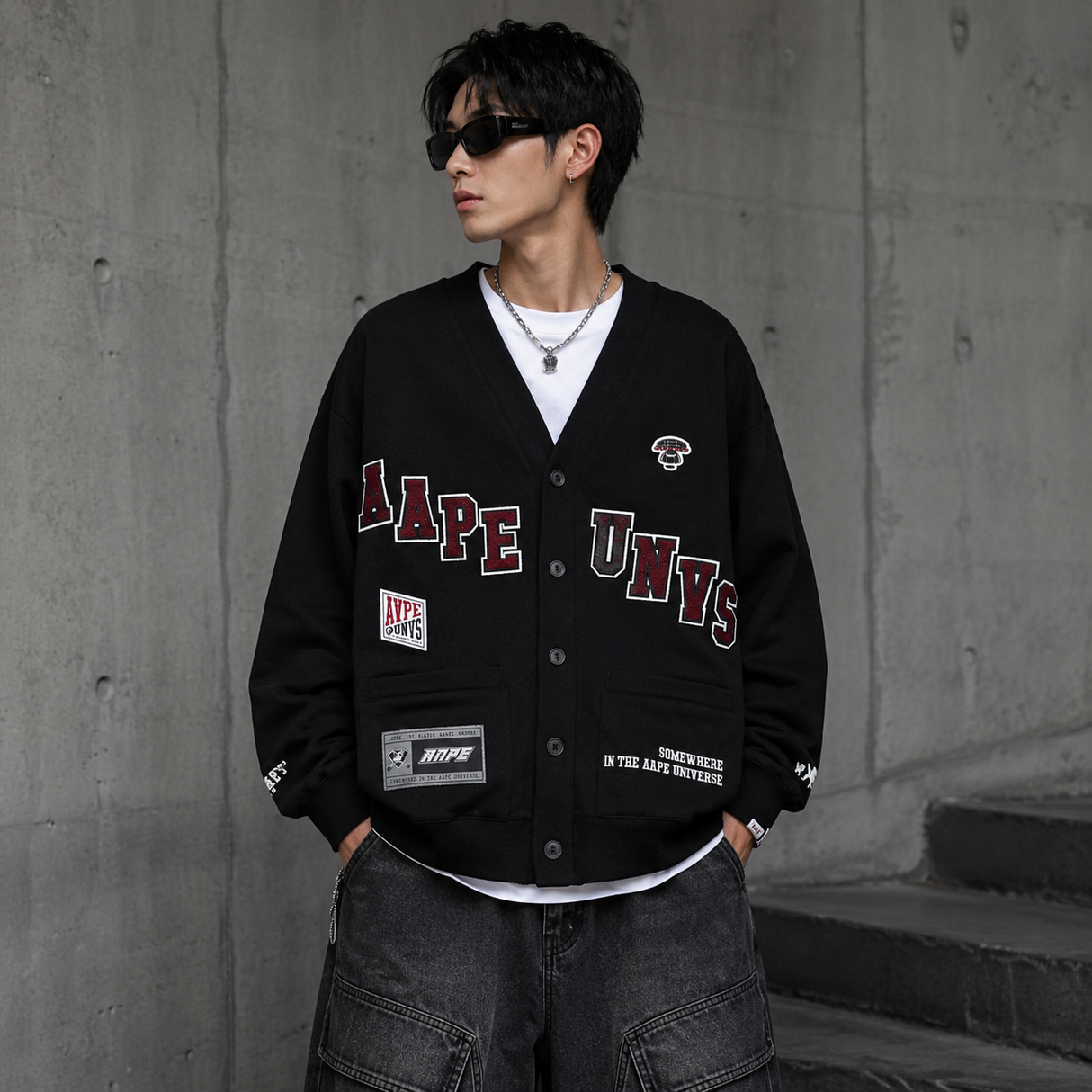 AAPE By Bathing Ape UNVS cardigan in gray with logo embroidery, displayed on a hanger showcasing its knit texture and casual style.