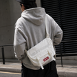 Supreme reflective logo denim messenger bag in white with adjustable strap and front logo patch, casual style accessory.