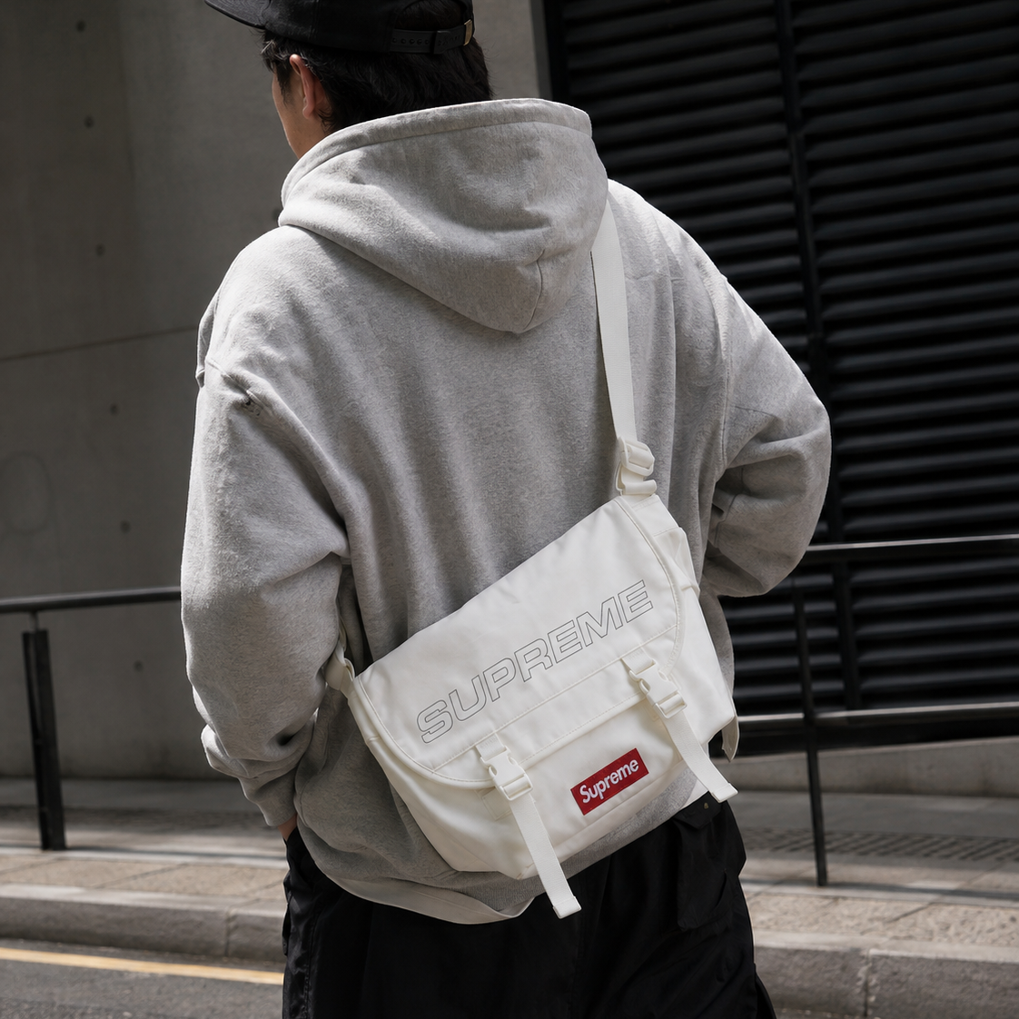 Supreme reflective logo denim messenger bag in white with adjustable strap and front logo patch, casual style accessory.