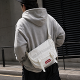 Supreme reflective logo denim messenger bag in white with adjustable strap and front logo patch, casual style accessory.