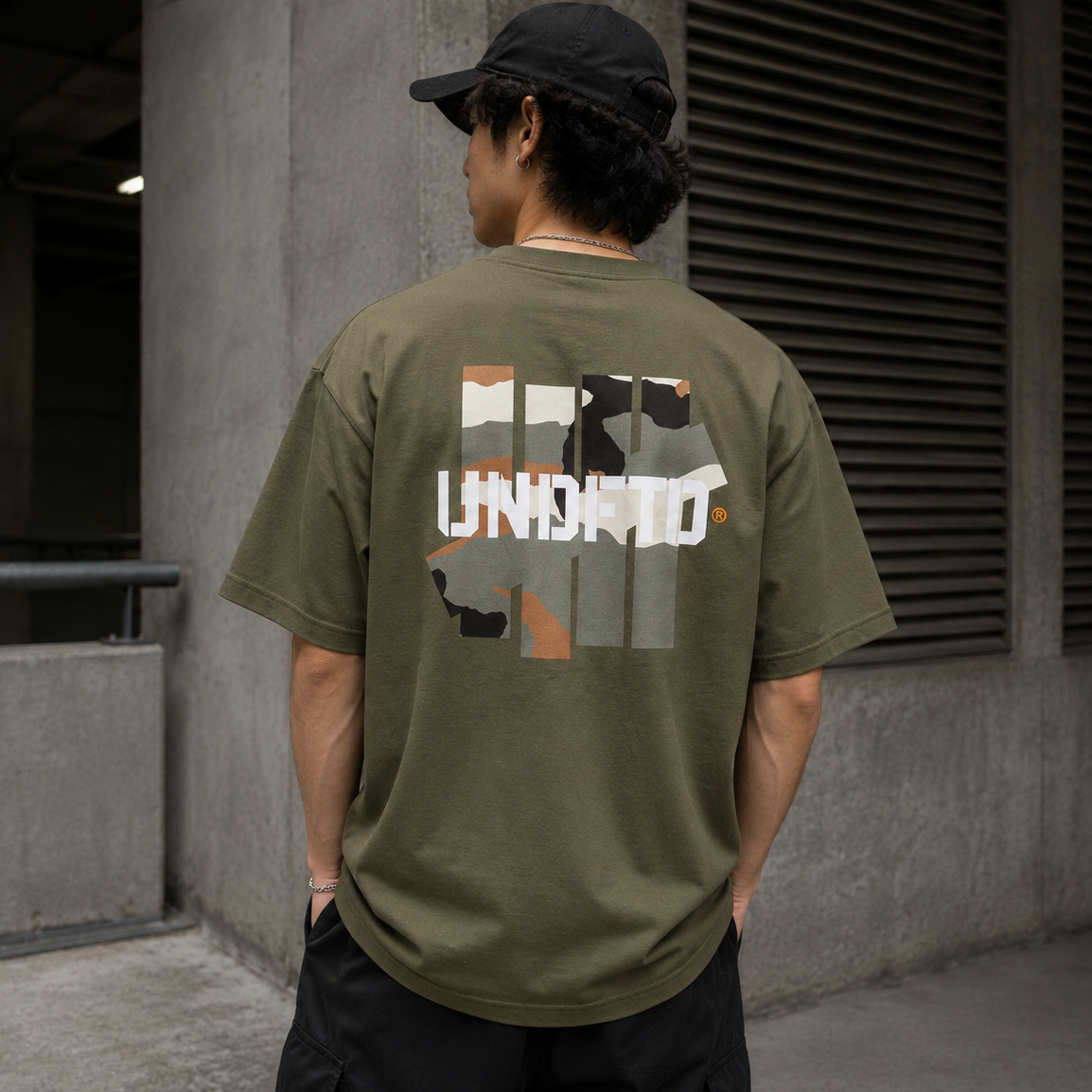 Undefeated Camo Icon Tee in olive green displayed on a hanger, showcasing the camouflage pattern and brand logo.