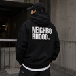 Black Neighborhood Classic Zip Hoodie displayed on a hanger, featuring the brand's logo on the chest and a front zipper.