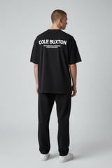 Black Cole Buxton Signature Tee displayed on a hanger, showcasing the classic design and soft cotton fabric.