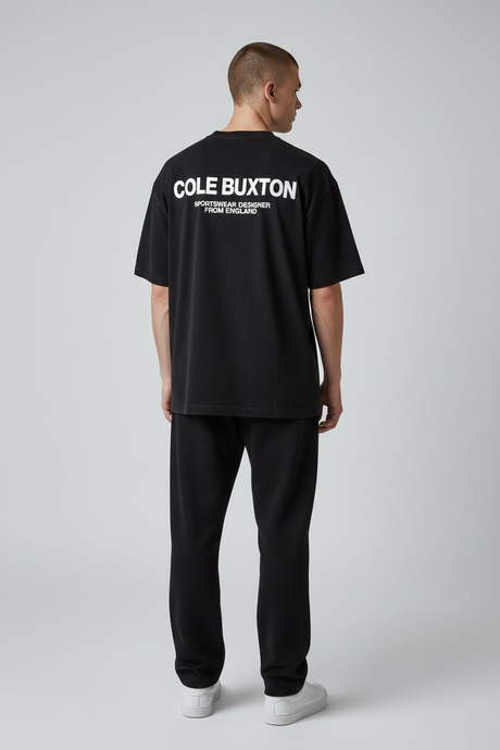 Black Cole Buxton Signature Tee displayed on a hanger, showcasing the classic design and soft cotton fabric.