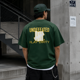 Undefeated Trademark Tee in forest green, casual men's t-shirt with bold logo design, laid flat on a white background.