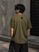 Olive green Undefeated stencil logo t-shirt with short sleeves and crew neck, casual streetwear style.