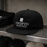 Black Undefeated logo snapback hat with adjustable strap and embroidered branding, designed for casual headwear style.