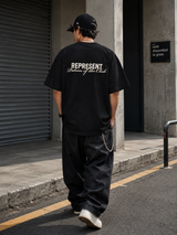 Black Represent Patron of the Club Tee featuring the brand logo and design on the front, styled for casual wear.