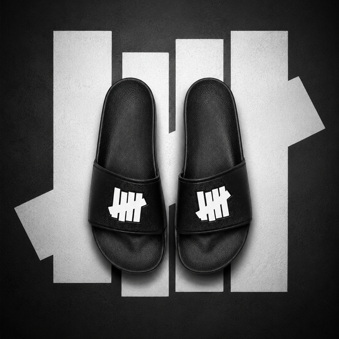 Black Undefeated Signature Logo Slides shoes with bold branding and comfortable slide design, perfect for casual wear.