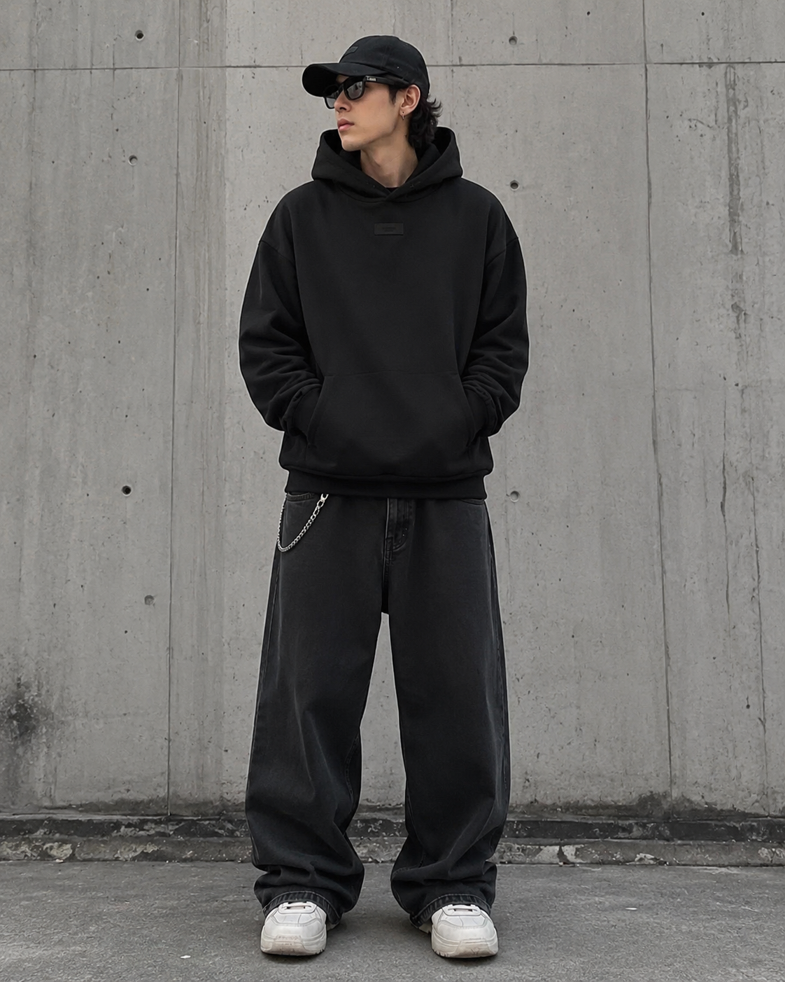 Black Fear of God Essentials hoodie with applique box logo, featuring a relaxed fit and modern streetwear style.