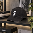 Black Supreme S Logo cap, a stylish headwear accessory featuring the iconic Supreme branding and classic baseball cap design.
