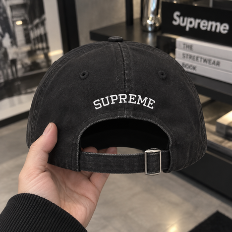 Black Supreme S Logo Cap, a stylish headwear with the iconic Supreme branding and adjustable strap.